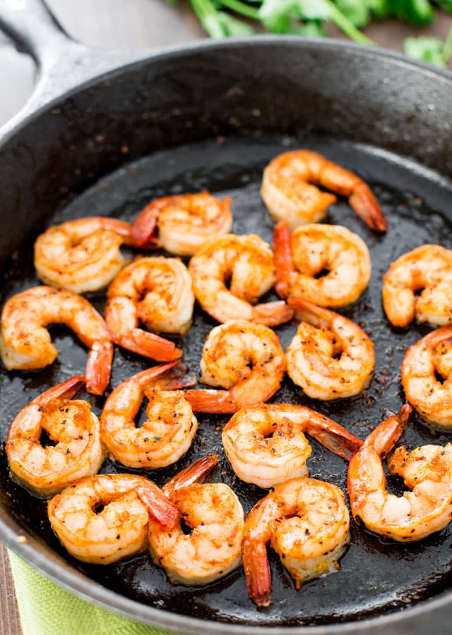 a black skillet with cooked shrimp