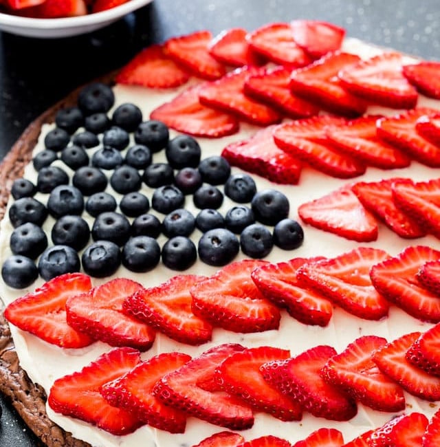 brownie pizza topped with cream cheese, fresh strawberries and blueberries to resemble the american flag