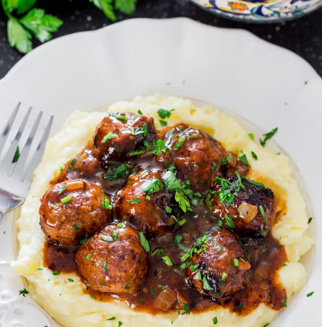 a plate of mashed potatoes topped with salisbury steak meatballs and gravy