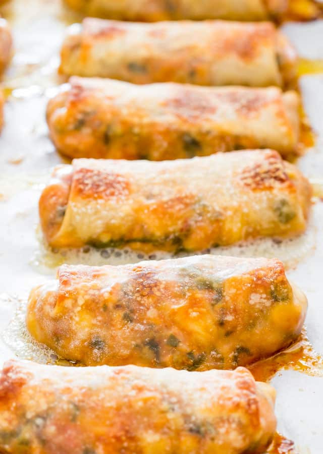 a bunch of mexican chicken egg rolls on a baking sheet lined with parchment paper