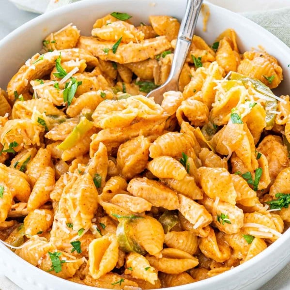 sideview shot of chicken fajita pasta in a white bowl with a fork inside