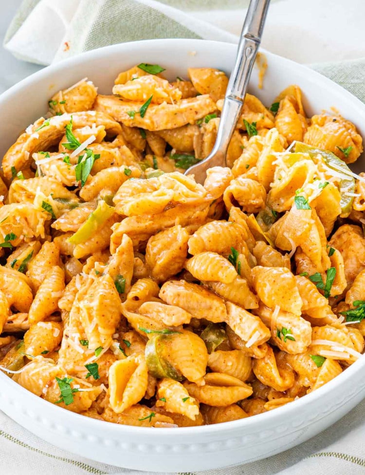sideview shot of chicken fajita pasta in a white bowl with a fork inside