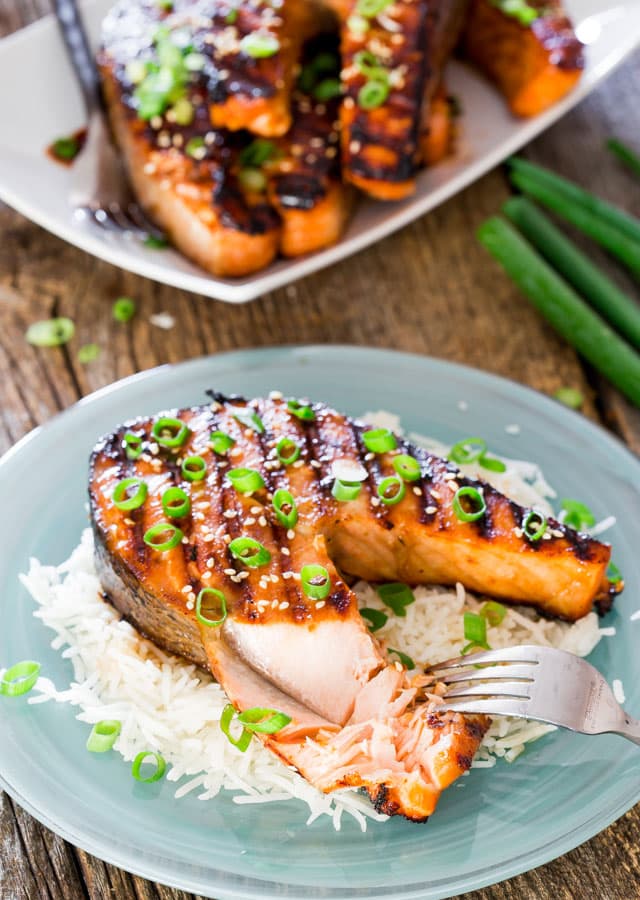 a Maple Soy Grilled Salmon Steak on a bed of rice with a fork flaking some of the salmon