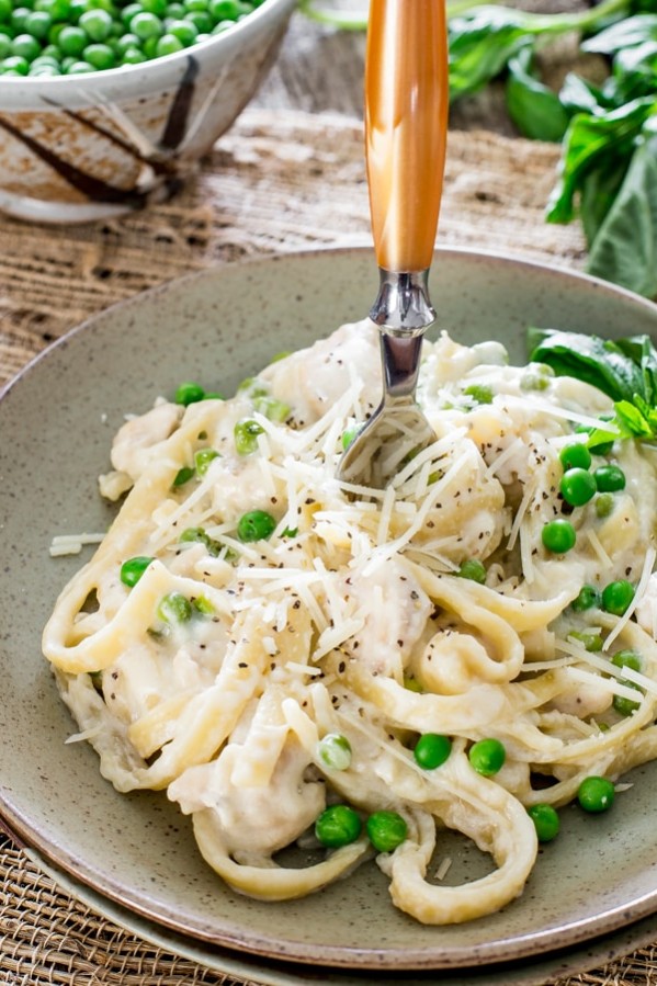 chicken and peas fettuccine alfredo with a fork stuck in it