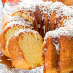 sliced bermuda rum cake topped with caramel sauce and shredded coconut