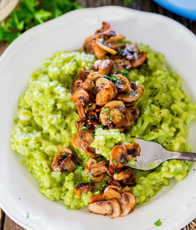 a fork taking a bite of arugula and basil risotto with sauteed mushrooms