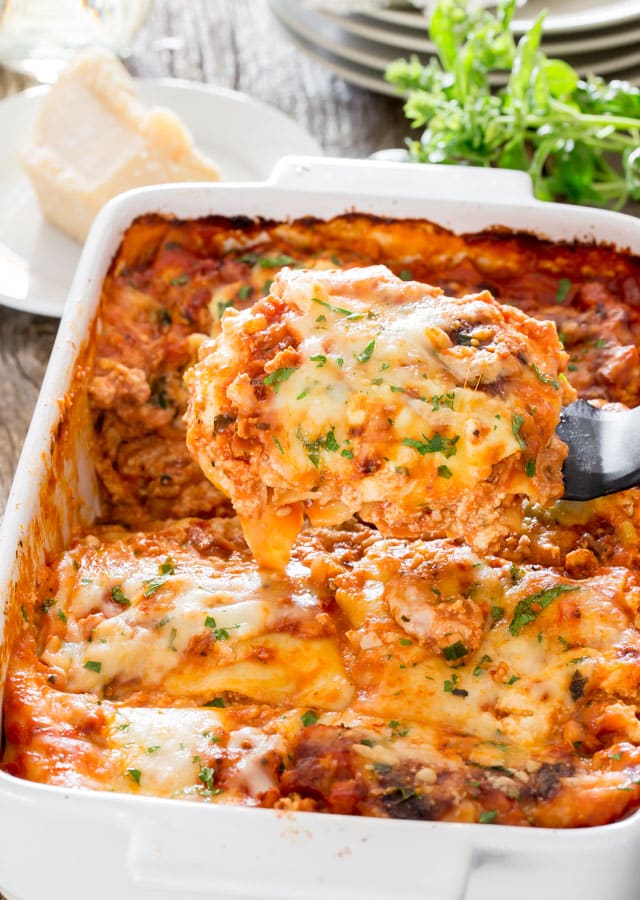a spatula lifting a piece of chicken bolognese lasagna from the baking dish