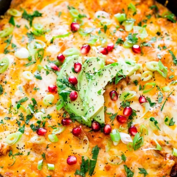 chicken tamale casserole topped with slices of avocado and pomegranate seeds
