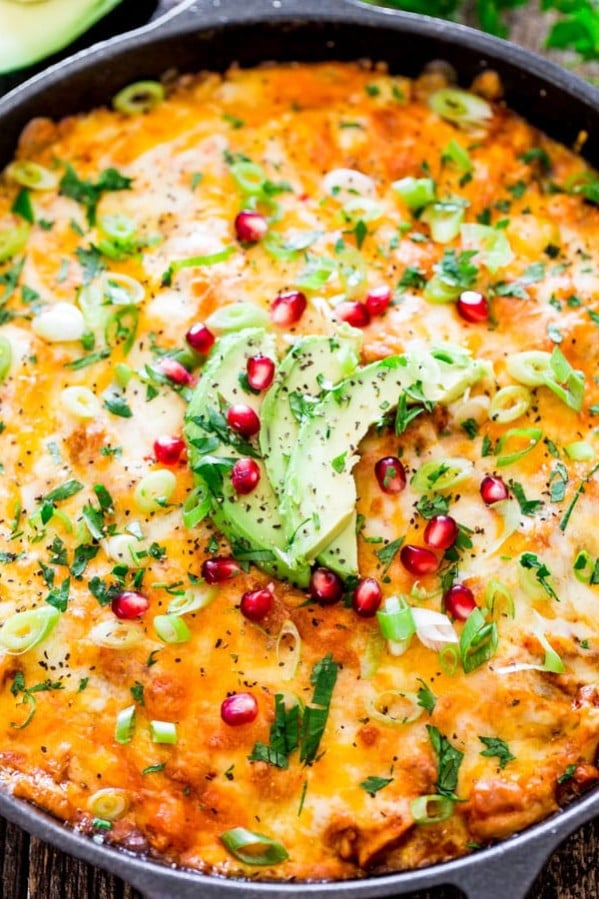 chicken tamale casserole topped with slices of avocado and pomegranate seeds