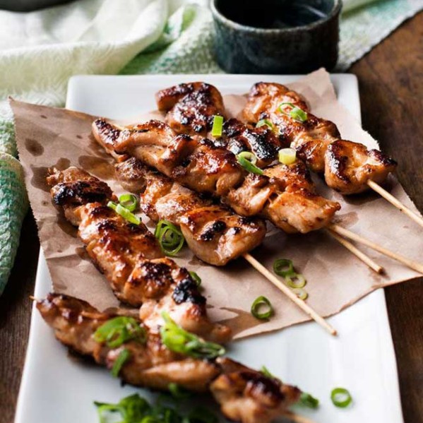 chinese chicken skewers garnished with green onions on a plate