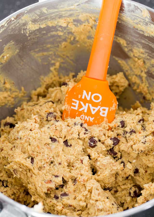 Hazelnut Toffee Chocolate Chip cookie dough in the bowl of a mixer with a spatula inside