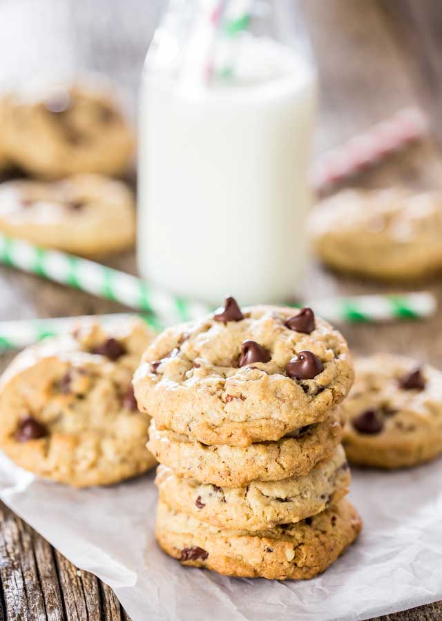 a stack of Hazelnut Toffee Chocolate Chip Cookies on a piece of parchment paper with a glass of milk in the background