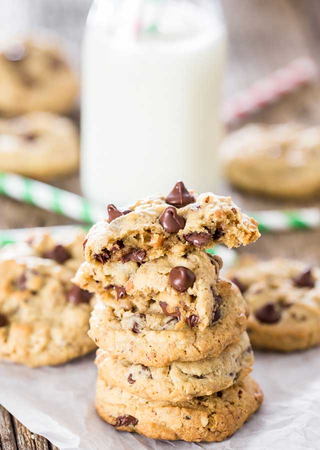 a stack of hazelnut toffee chocolate chip cookies with the top one split in half