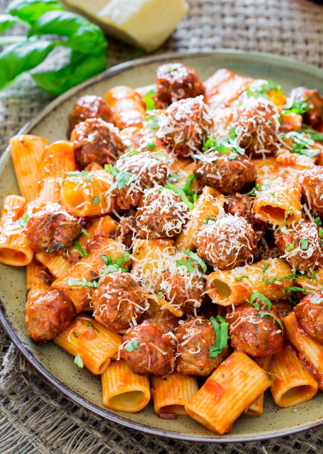 a plate loaded with Rigatoni con Polpette and Arrabiata Sauce and garnished with parmesan cheese