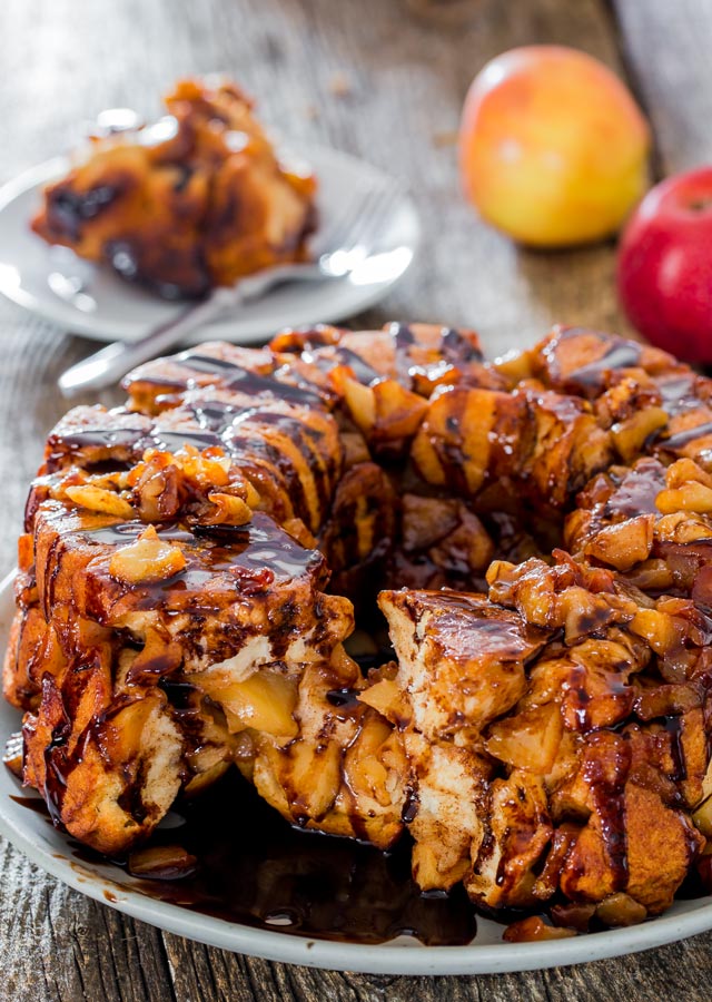 delicious apple pie monkey bread drizzled with chocolate sauce on a plate with a piece taken out
