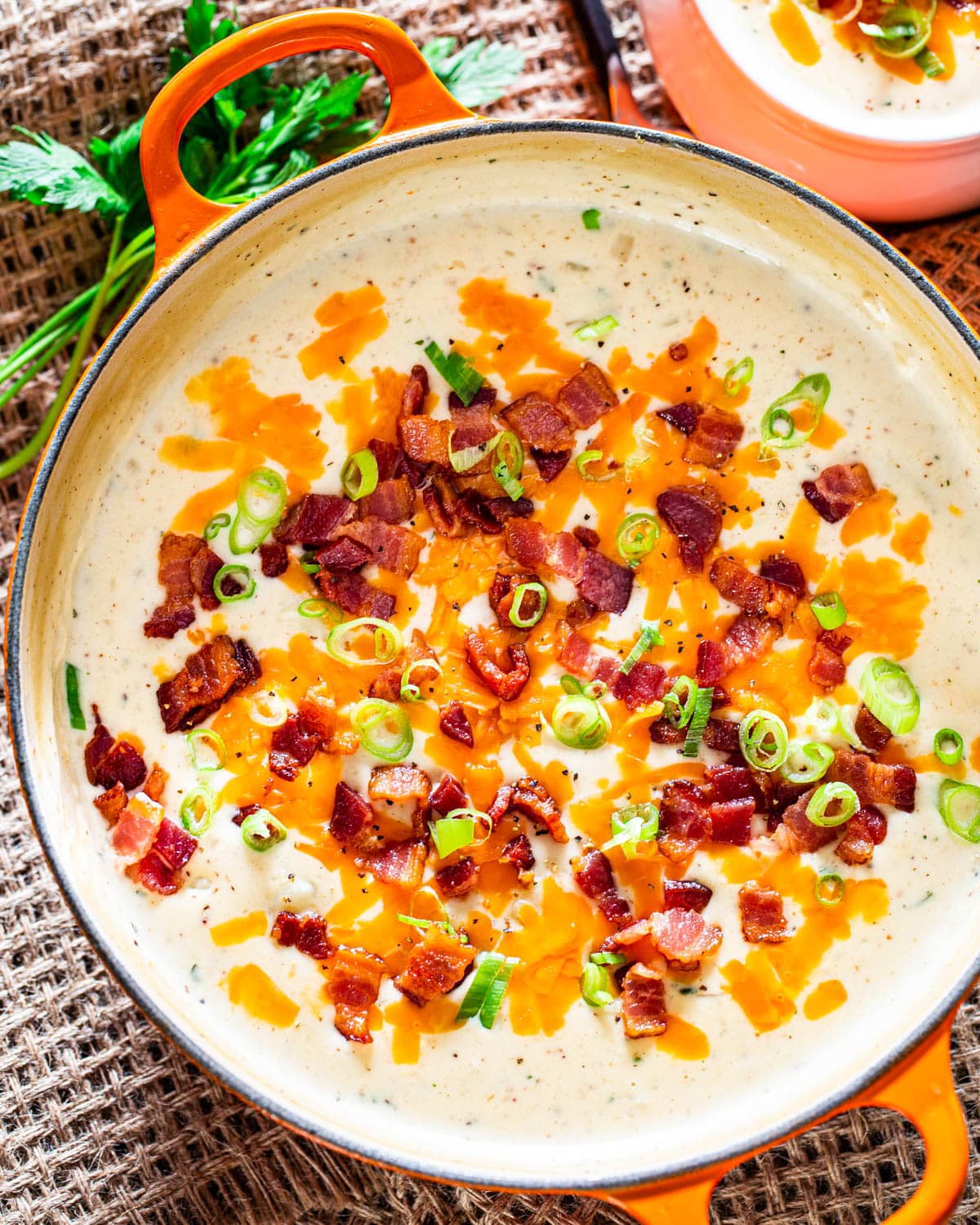 overhead shot of potato soup in a large Dutch oven garnished with cheese, bacon and green onions
