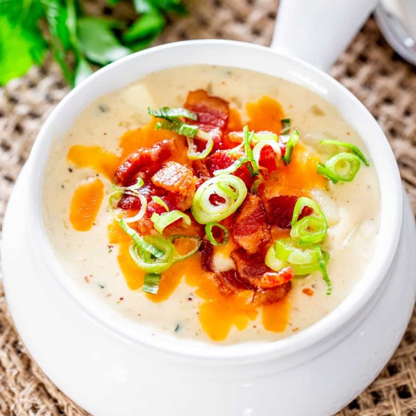 overhead shot of a bowl of potato soup topped with cheese, chopped bacon and sliced green onions