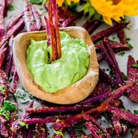 a bowl of avocado aioli surrounded by purple yams