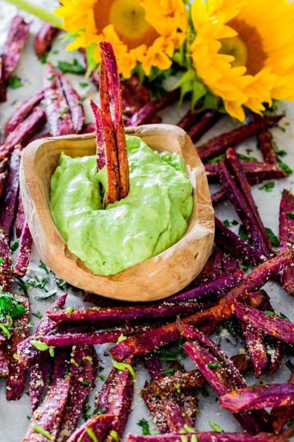 a bowl of avocado aioli surrounded by purple yams