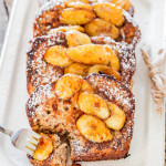 a fork taking a bite of banana bread french toast with caramelized bananas on a plate