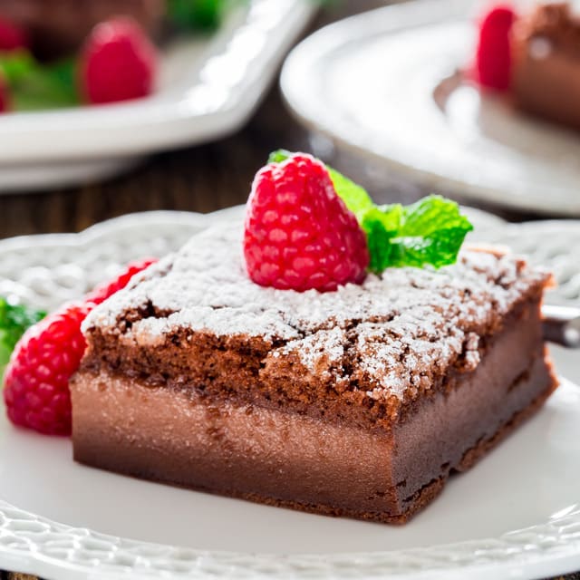 a slice of nutella magic cake dusted with powdered sugar and topped with a fresh raspberry