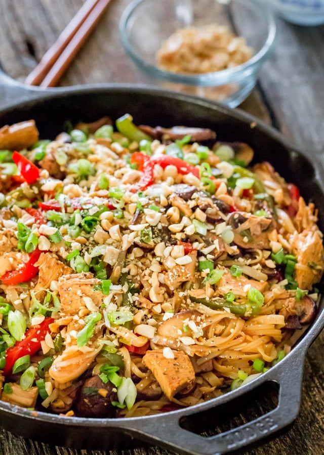 Spicy Thai Chicken and Veggie Noodles in a skillet topped with peanuts