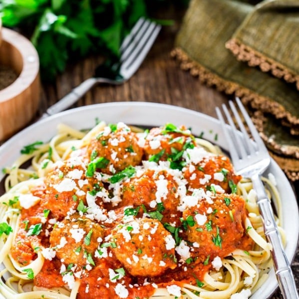 a plate of pasta topped with cajun meatballs in fire roasted tomato sauce