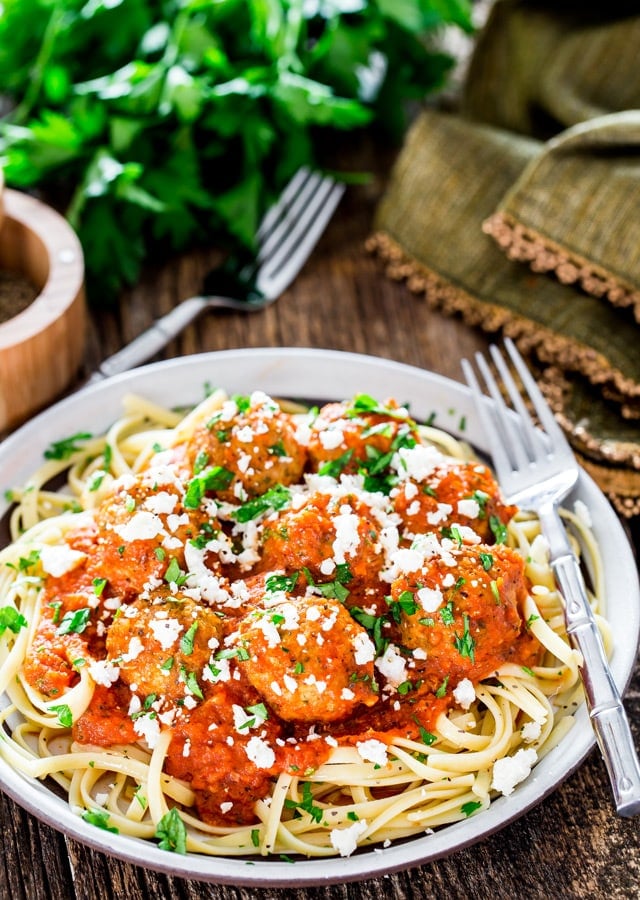 a plate of pasta topped with cajun meatballs in fire roasted tomato sauce