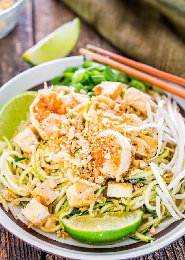 a plate of pad thai zoodles garnished with lime wedges