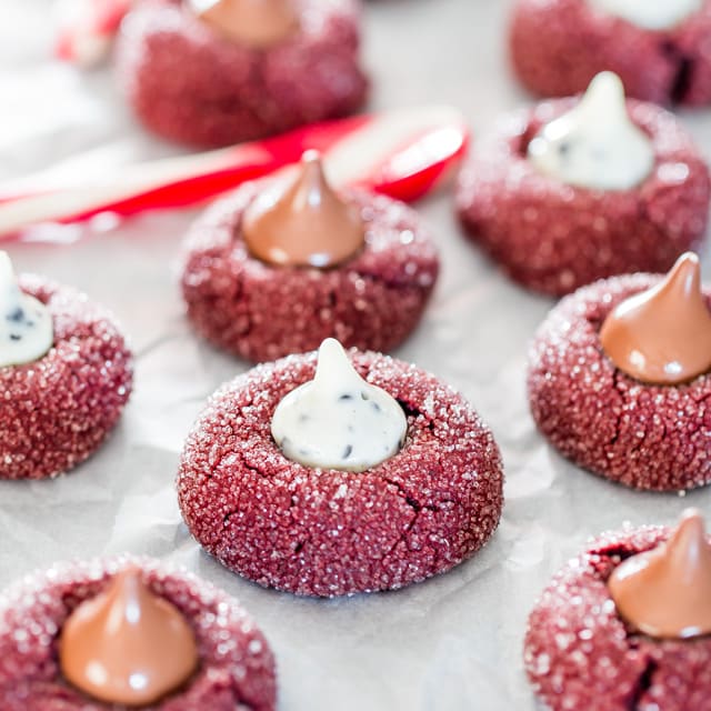 closeup of Red Velvet Kiss Cookies on parchment paper with a candy cane