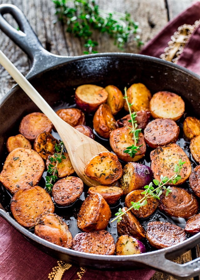 Skillet Potatoes with a wooden spoon and three sprigs of thyme