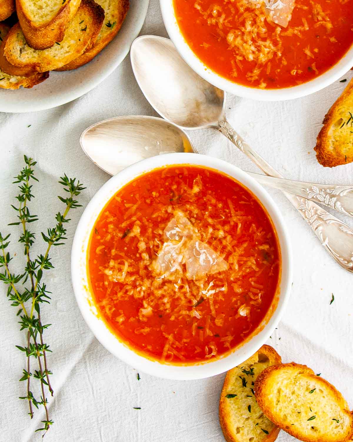 overhead shot of roasted tomato soup in 2 white bowls with toasted slices around.