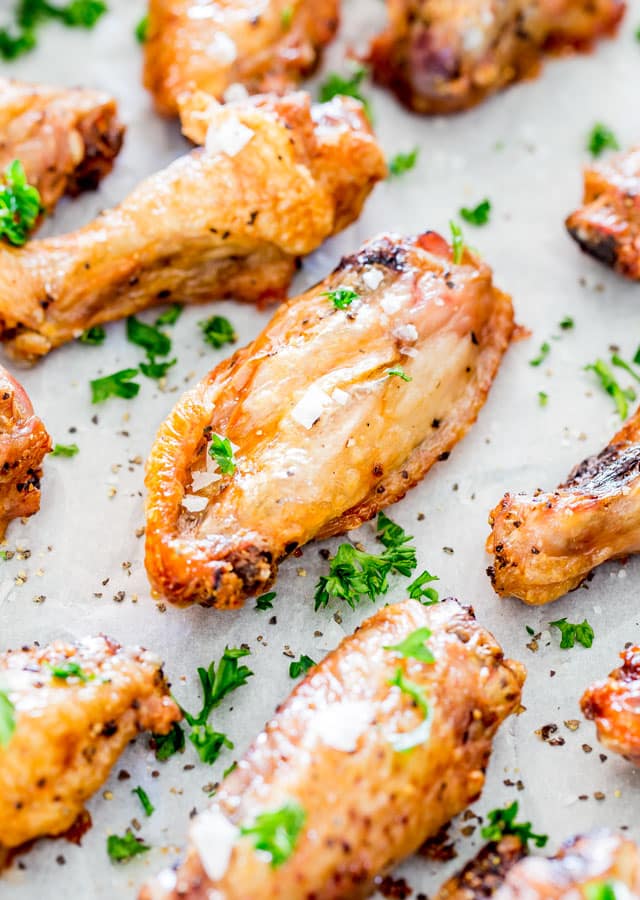 Crispy Baked Salt and Pepper Chicken Wings on a baking sheet garnished with sea salt and parsley