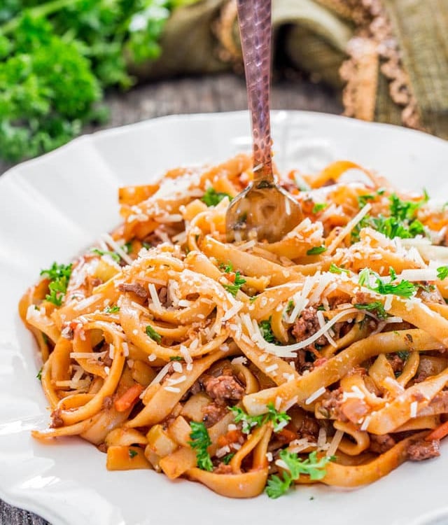 a fork twirling the fettuccine with beef ragu on a plate