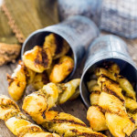 side view shot of two metal buckets tipped over with parmesan pesto twists spilling out