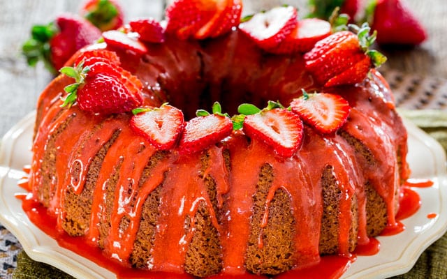 a strawberry glazed pound cake on a serving platter garnished with strawberries