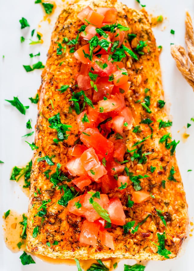 overhead of a filet of lemon garlic halibut topped with chopped tomatoes and parsley