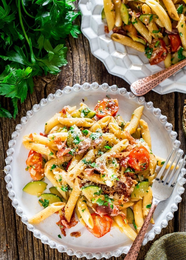overhead of a plate of Penne with Prosciutto with a fork