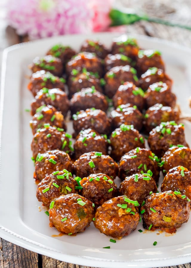 Korean Meatballs lined up on a white platter topped with chives
