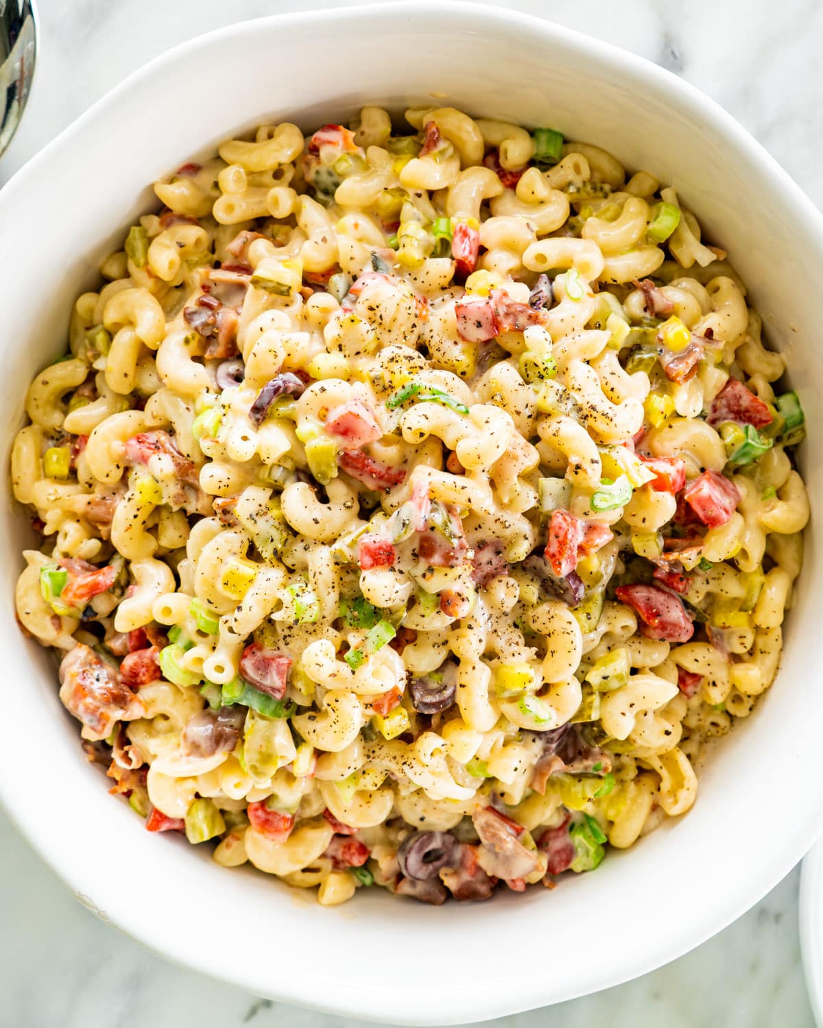 overhead shot of macaroni salad with prosciutto in a big white bowl