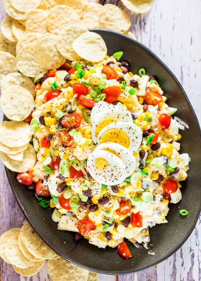 overhead shot of tex mex potato salad on a serving platter surrounded by tortilla chips
