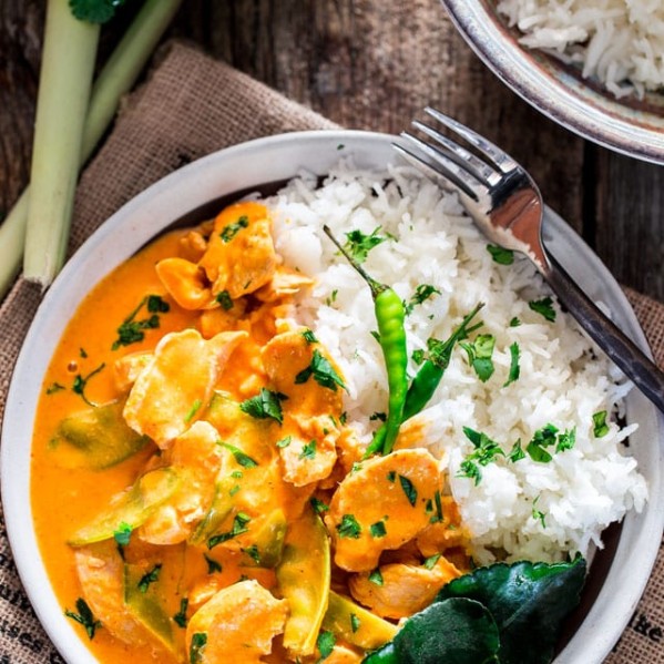 overhead shot of a bowl of thai red chicken curry with a side of rice