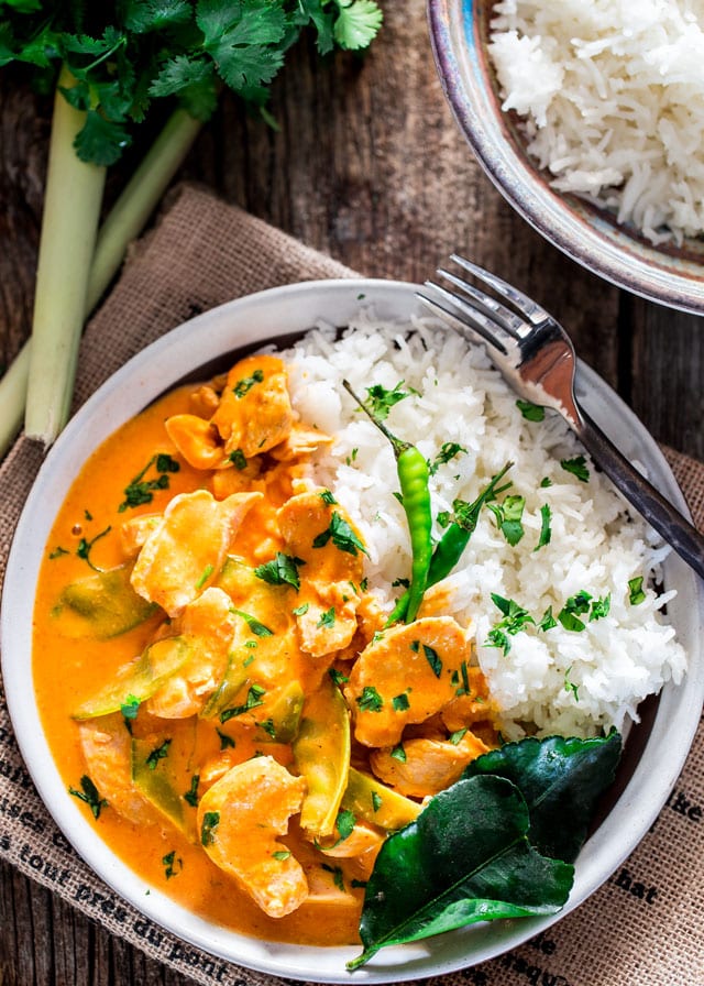 overhead shot of a bowl of thai red chicken curry with a side of rice