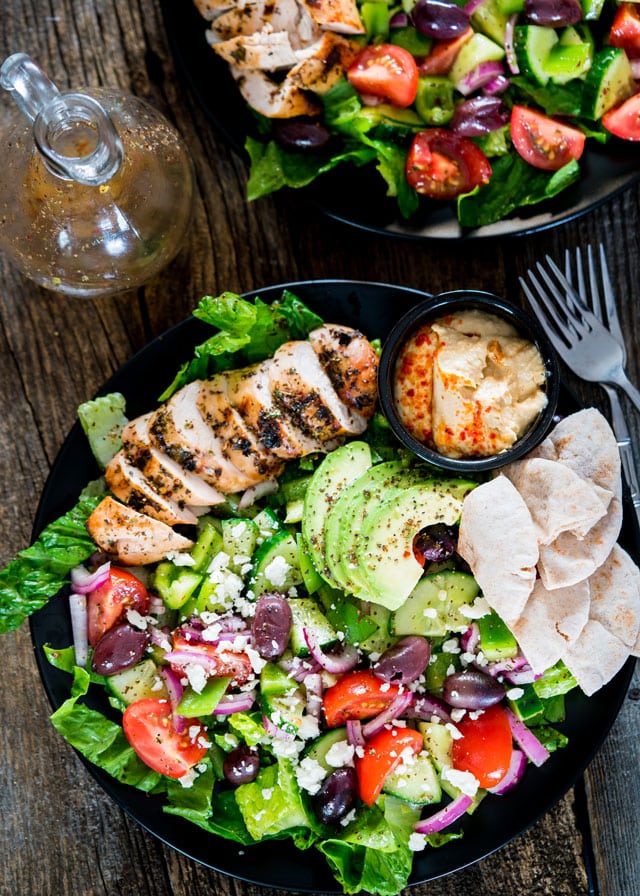 overhead of a plate of Mediterranean Grilled Chicken Salad with a side of hummus