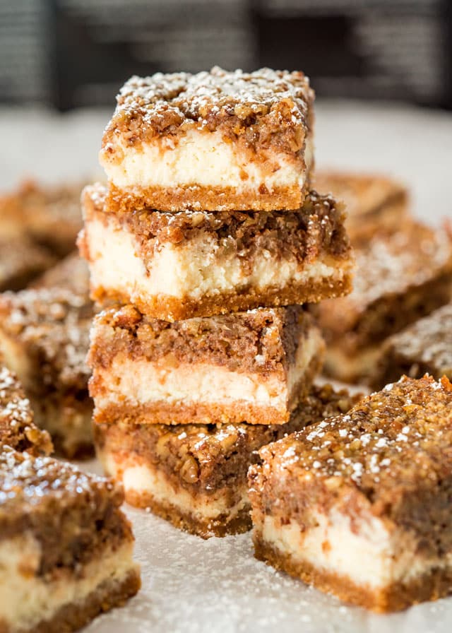 a stack of Pecan Pie Cheesecake Bars dusted with powdered sugar
