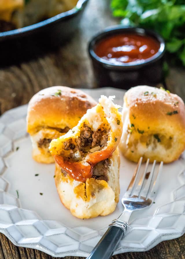 a bun stuffed with beef and cheese split in half on a plate