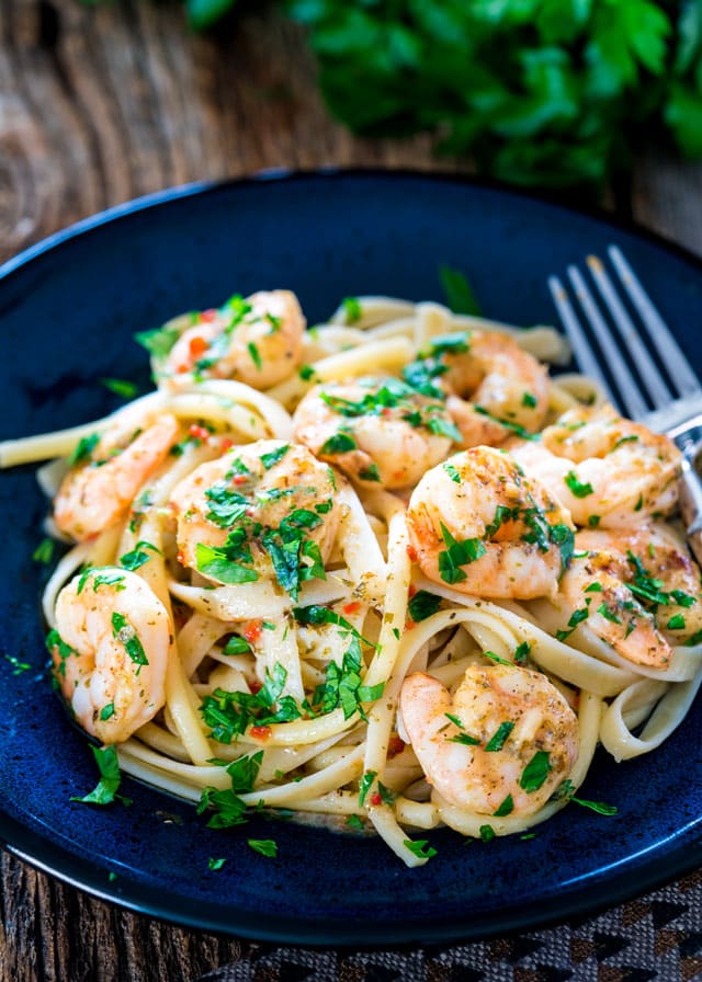 a plate of fettuccine topped with italian shrimp bake and parsley