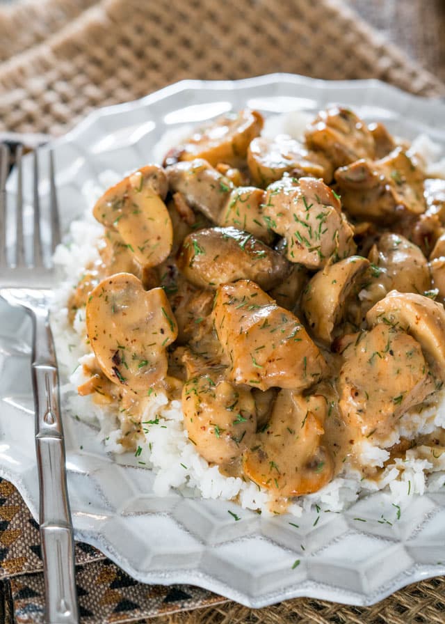 a plate of rice topped with mushrooms and chicken in a creamy sauce