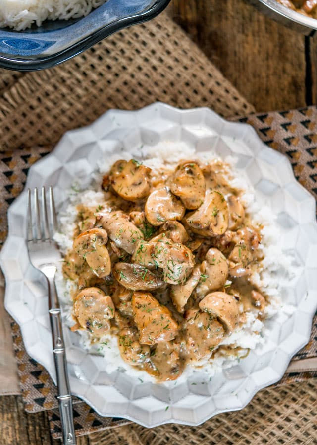 overhead of mushrooms and chicken with a creamy sauce over rice with a fork