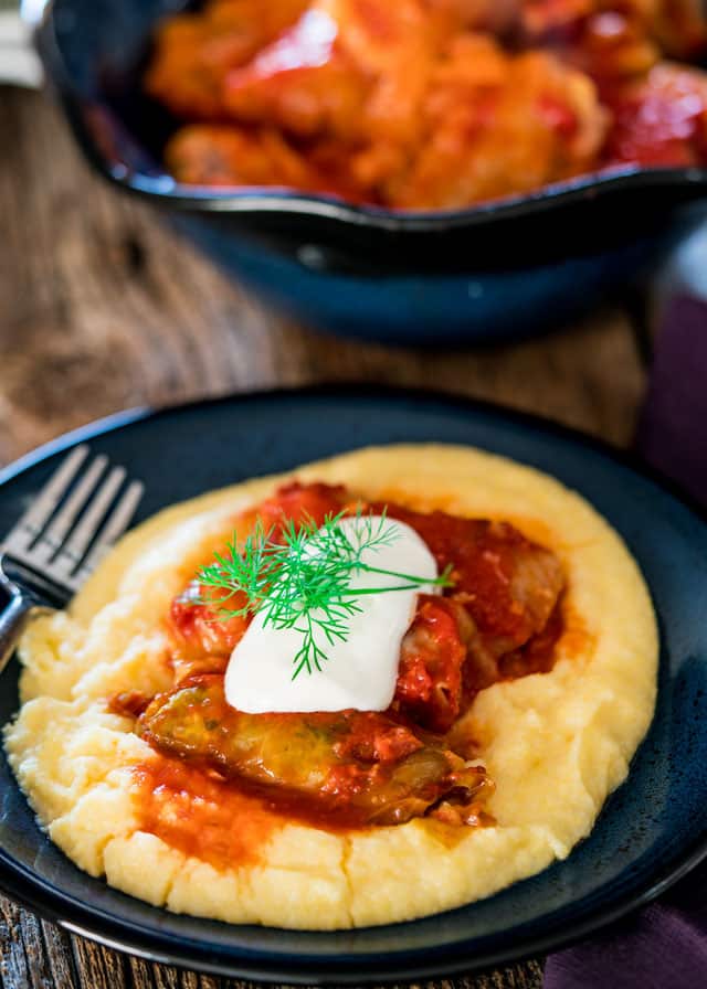 cabbage rolls made in a crockpot over polenta in a blue plate